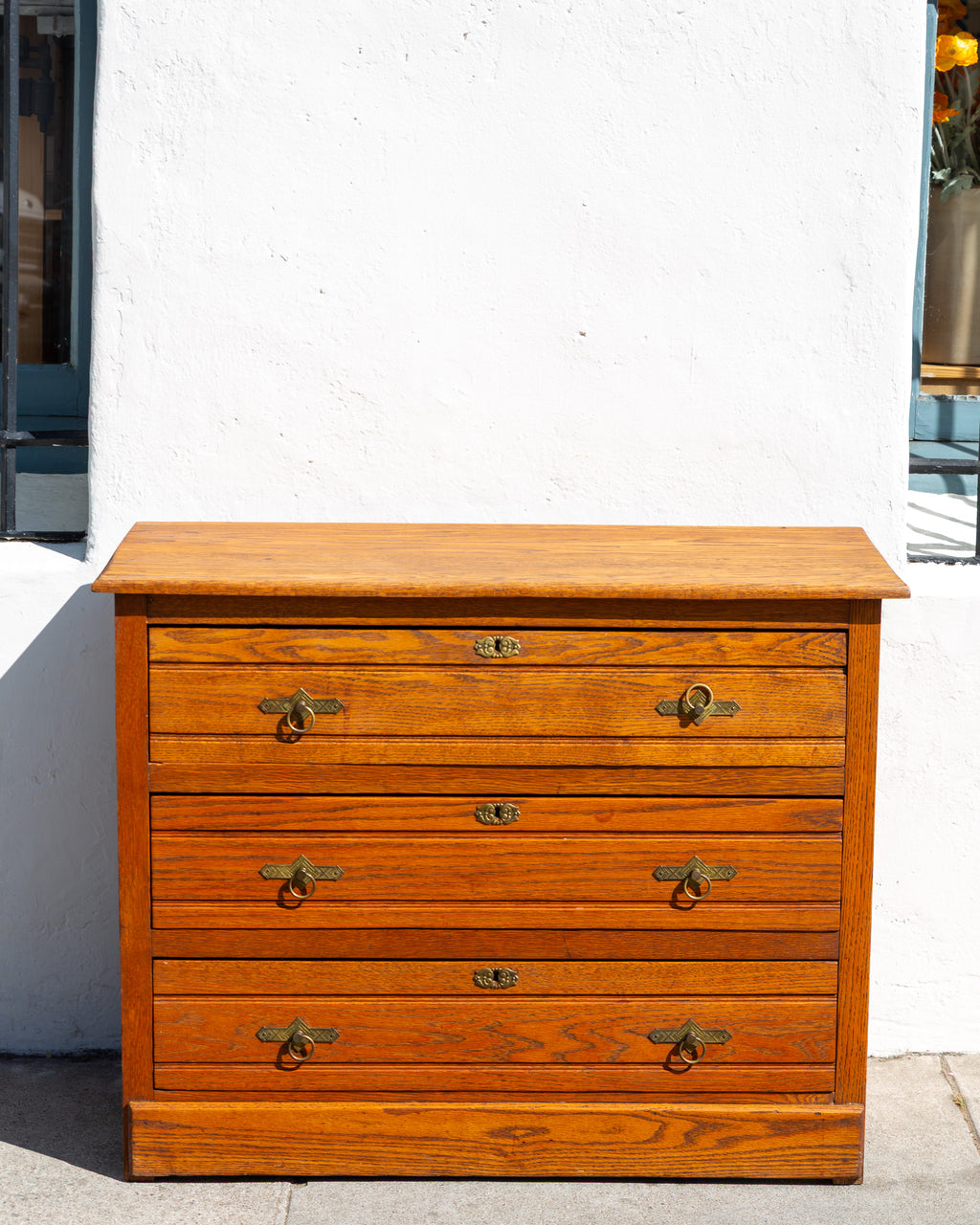 Antique three drawer oak dresser with paneled sides and brass ring pulls
