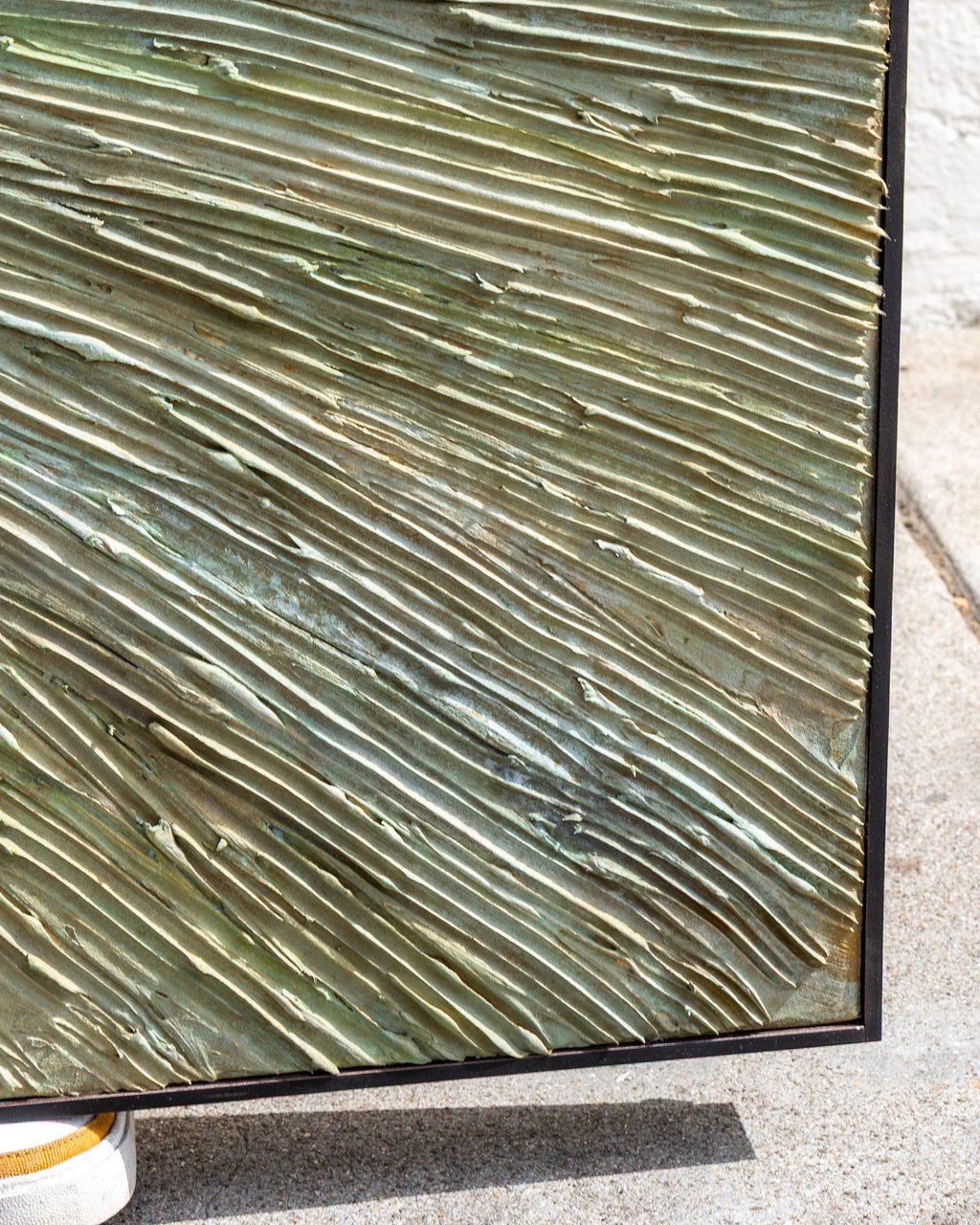 Detail of the painting's lower corner, diagonal ridges of pale green and sand impasto running to the frame.