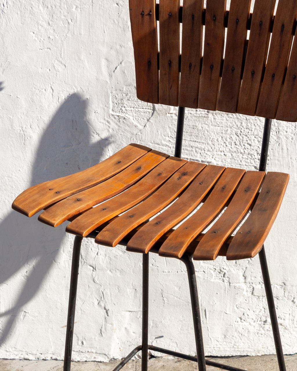 Detail of the curved wood slat seat of a bar stool with screws set into each slat