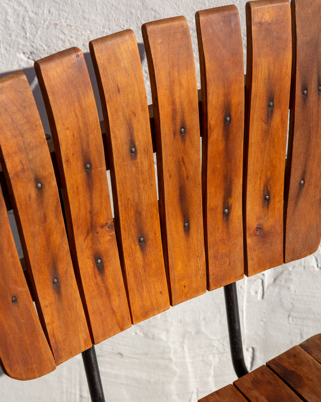 Close-up of honey-toned wood back slats with dark staining around the screw heads
