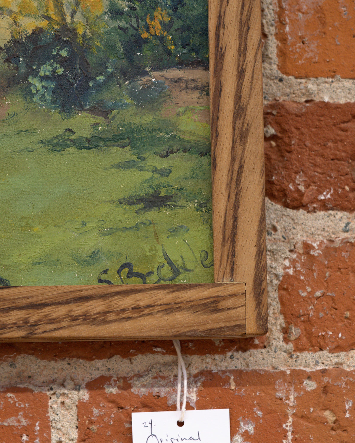 Detail of the signature on the Sheila Beckley English landscape painting with autumn trees, meadow and blue hills in a striped wood frame.