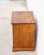 Side profile of an antique oak bin cabinet showing the heavily figured quarter-sawn side panel and molded base.