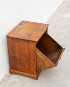 Three-quarter view of the oak bin cabinet with the tilt front swung fully open, revealing the deep bin.