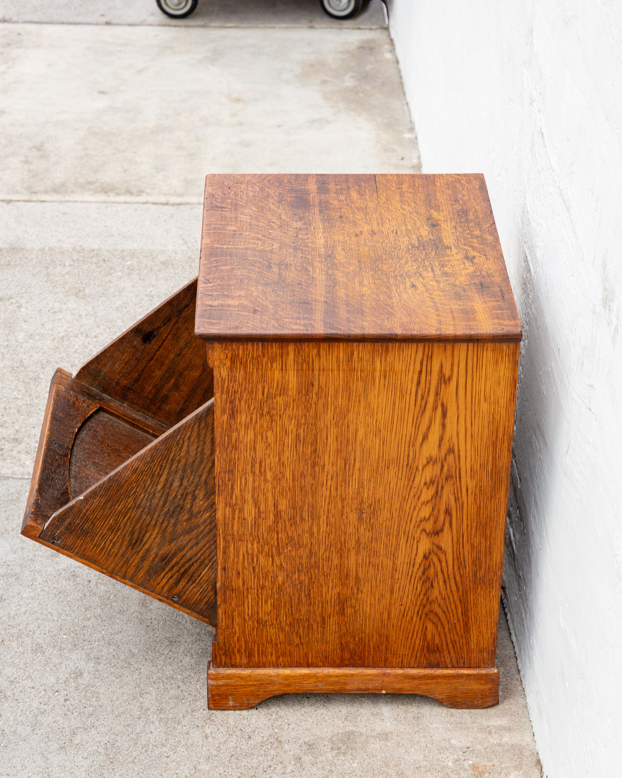 Overhead angled view of the tiger oak cabinet with the bin tilted open, showing the interior divider.