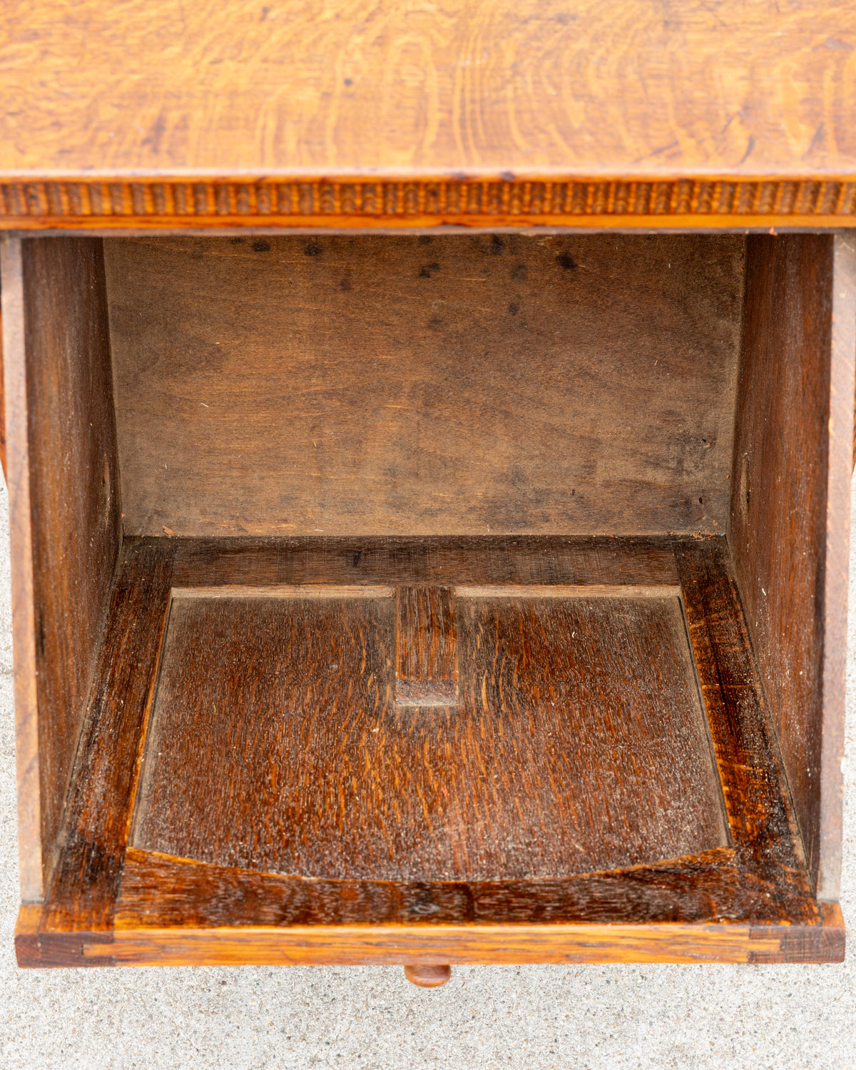 Looking down into the empty case of the oak bin cabinet, showing the unfinished interior floor and back panel.