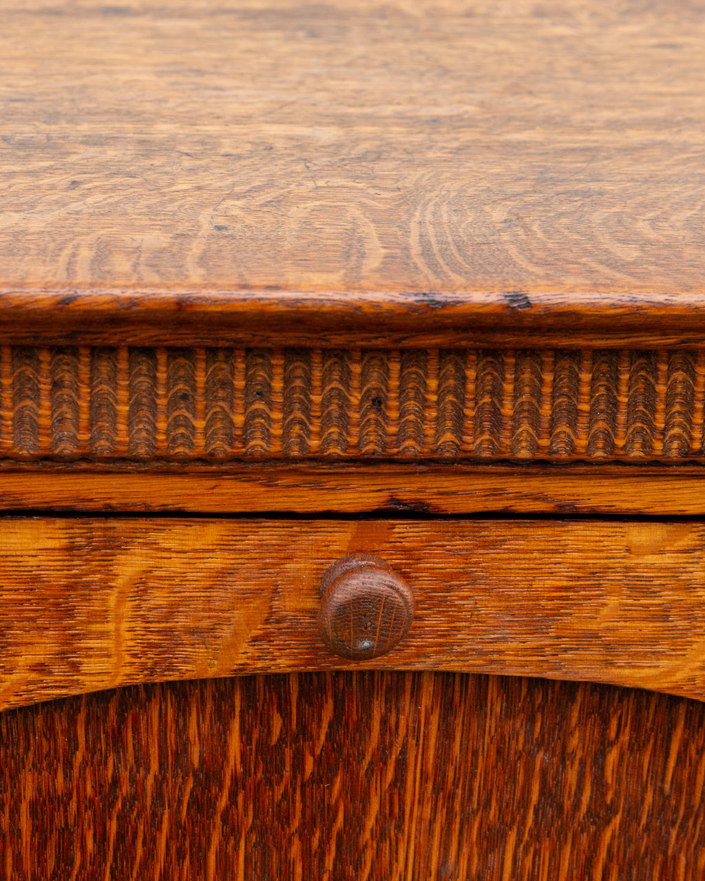 Close detail of the carved thumb molding band and turned wooden knob on the tiger oak bin cabinet.