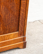 Detail of the opposite lower corner of the oak bin cabinet, showing the base molding and dark end-grain tenon.