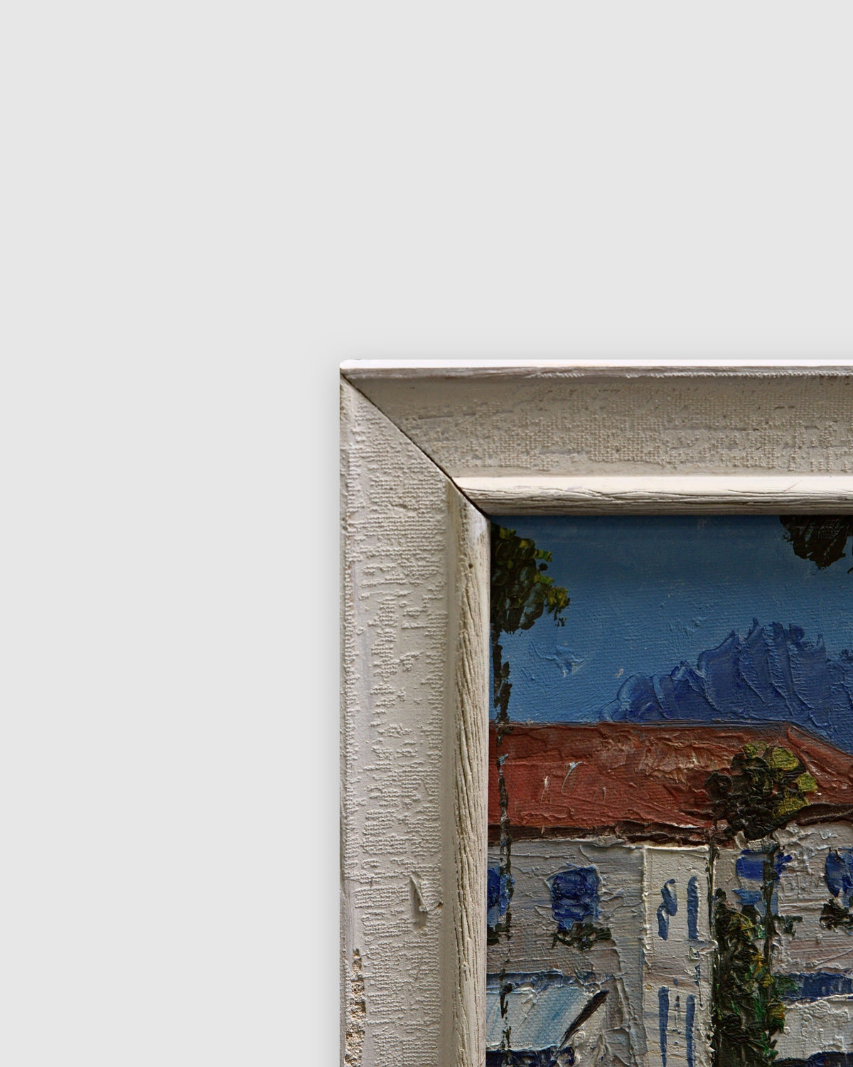 Angled view of the wide white textured frame at the top corner of the painting on a light gray background