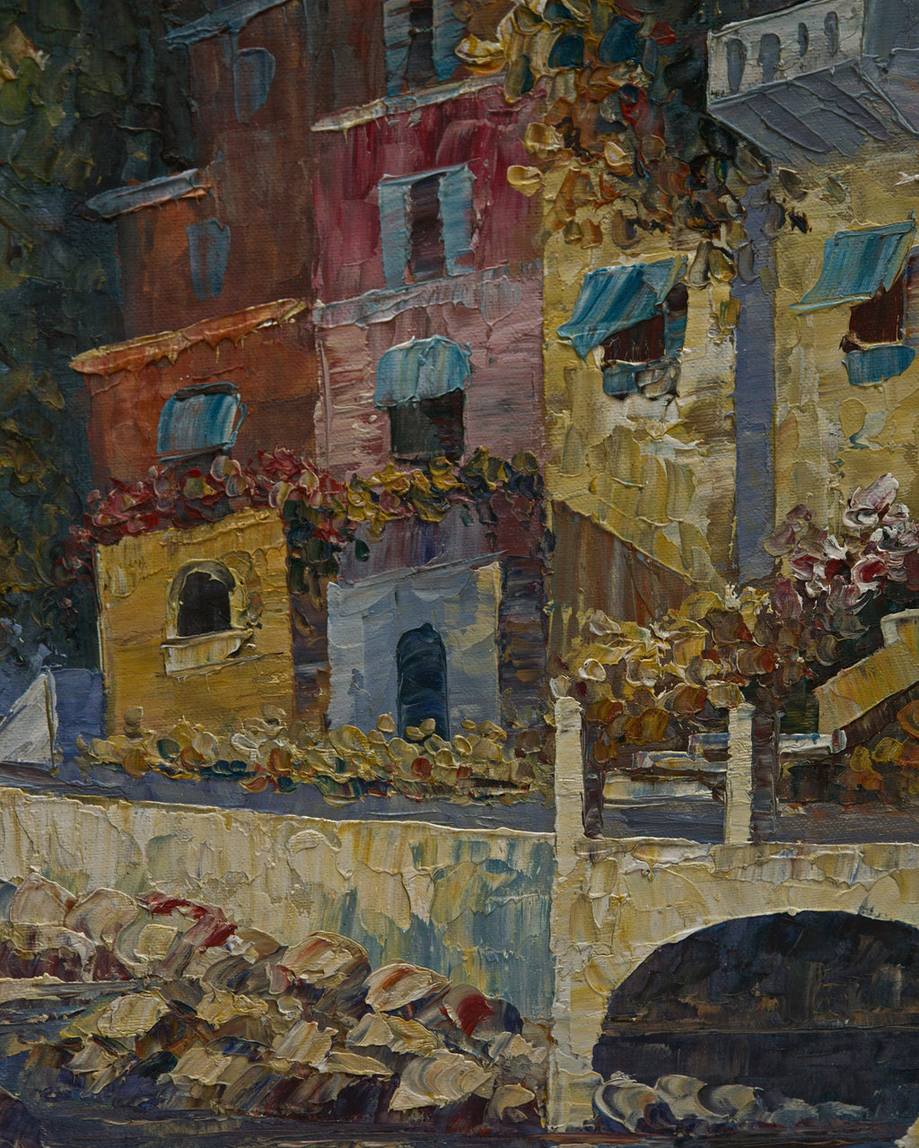 Detail of ochre, rose and coral harbor houses with blue awnings above a stone arched bridge
