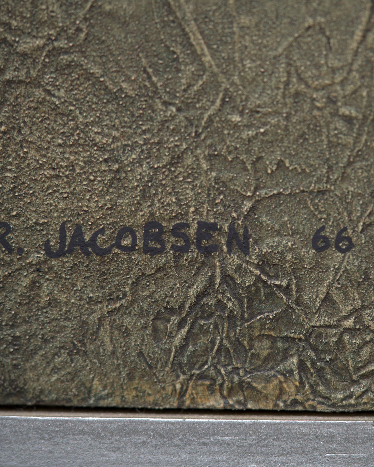 Detail of the signature on the Ray Jacobsen 1966 plaster relief abstract in slate blue, cream and olive in a silver strip frame.