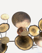 Right end of the Curtis Jere Raindrops sculpture, patinated brass discs and copper-toned cups on thin stems against a white wall.