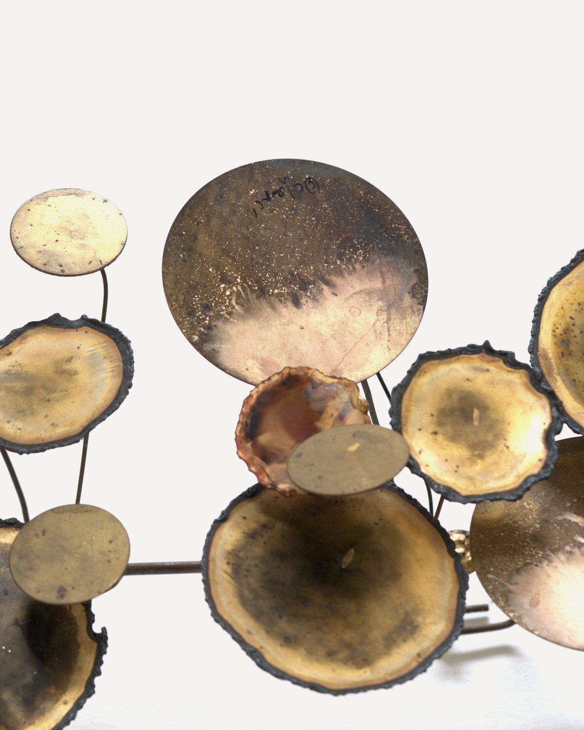 Right end of the Curtis Jere Raindrops sculpture, patinated brass discs and copper-toned cups on thin stems against a white wall.