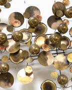 Center detail of the Raindrops sculpture showing polished brass spheres, torched discs and the black rod grid behind them.