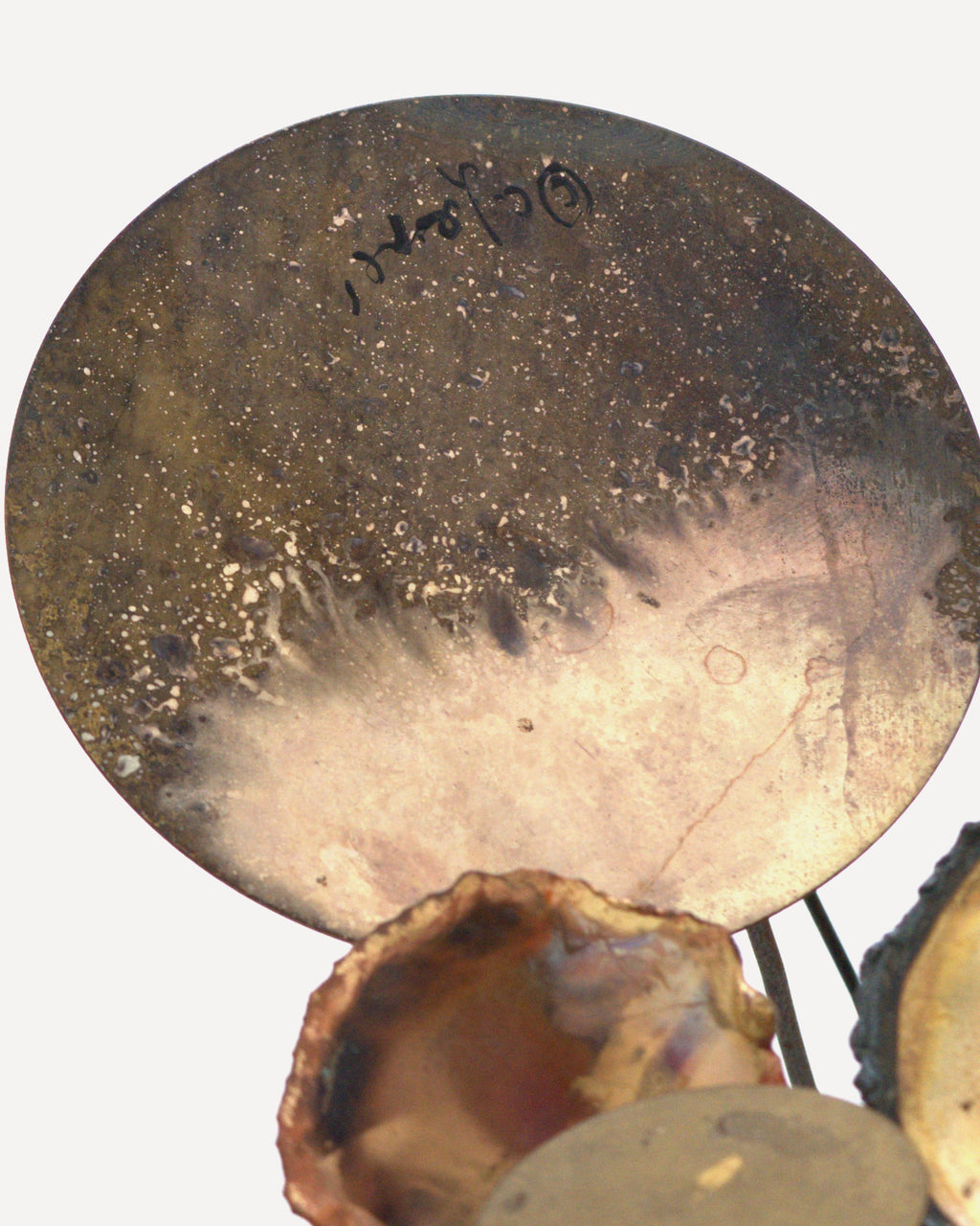 Detail of the C. Jere signature written in black on a patinated brass disc.