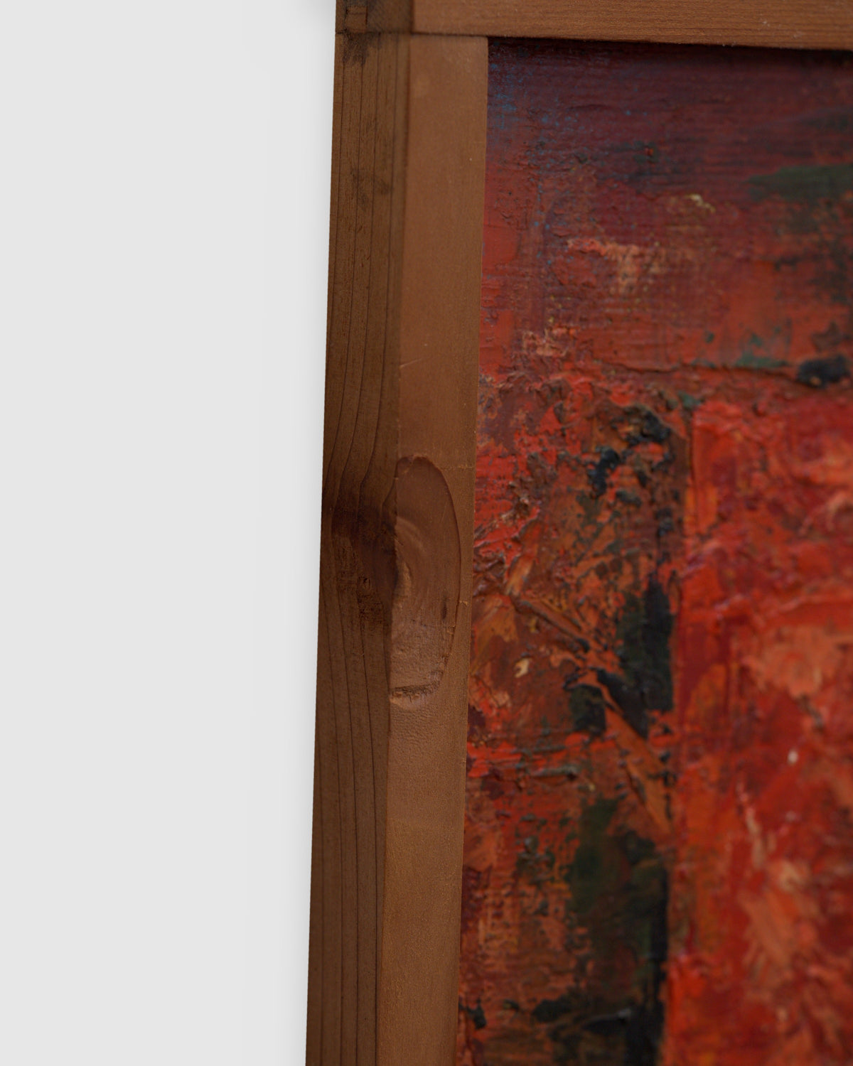 Side view of the frame edge on the mid century geometric abstract painting in red, mustard and teal impasto in a narrow wood frame.