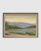 Straight-on view of a Joseph Knowles California desert landscape with lavender mountains and rabbitbrush in a gray frame with linen liner, on a light gray background.
