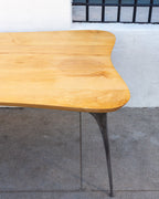 Second corner of a freeform maple table showing edge-joined boards and a cast aluminum leg.