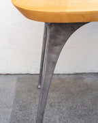 Close view of a cast aluminum table leg flaring into the underside of a thick maple top.