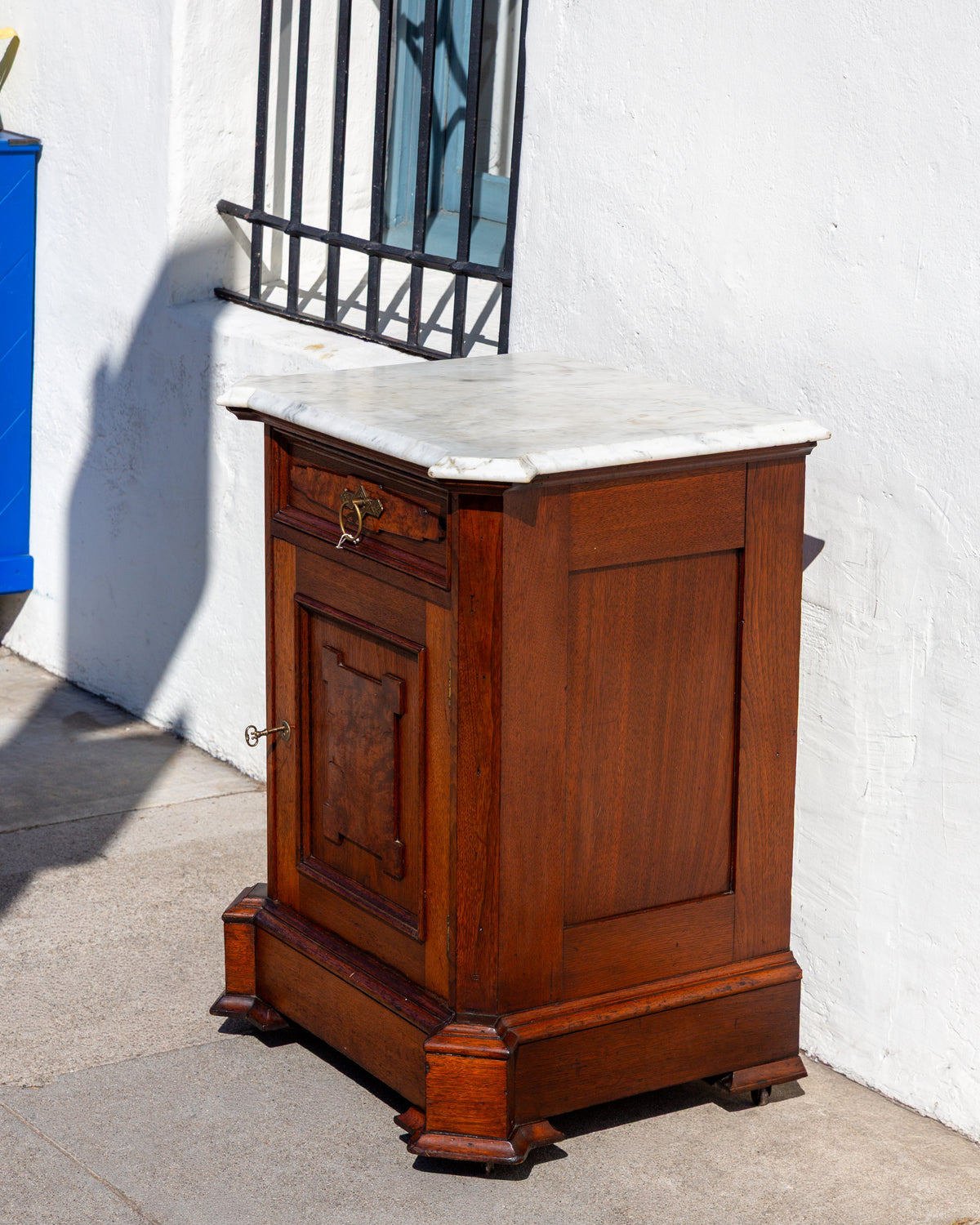Angled view of the marble top cabinet from the right, showing the canted front corners and blocked feet