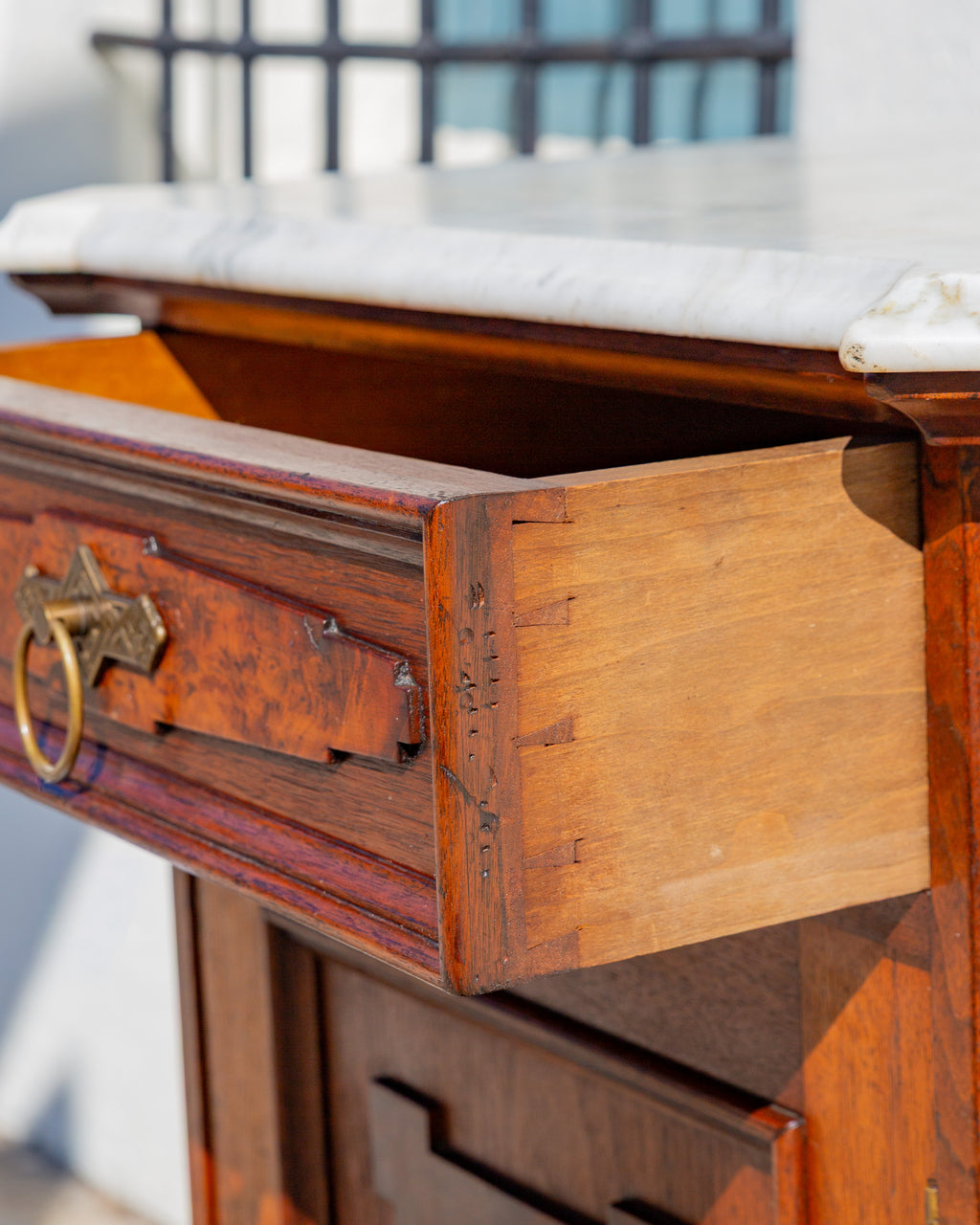 The drawer pulled open, showing hand cut dovetails at the corner and the underside of the marble top