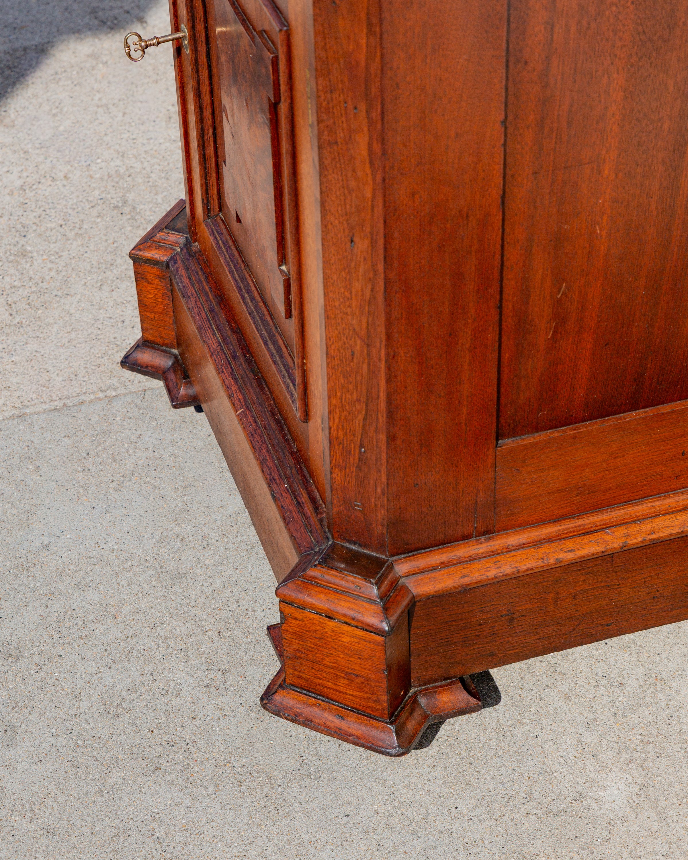 Detail looking down at the base moldings and blocked corner foot of the walnut cabinet