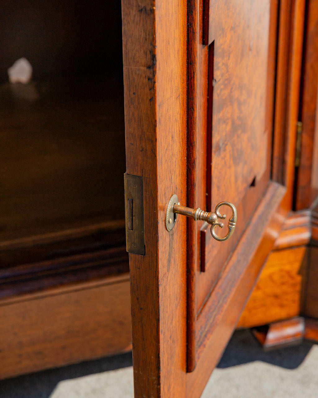 Detail of the brass key in the cupboard lock beside the brass strike plate on the open door edge