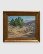 Straight-on view of a Jack McCartney desert landscape with a green smoke tree, sage and rose hills in a stepped gilt frame, on a light gray background.