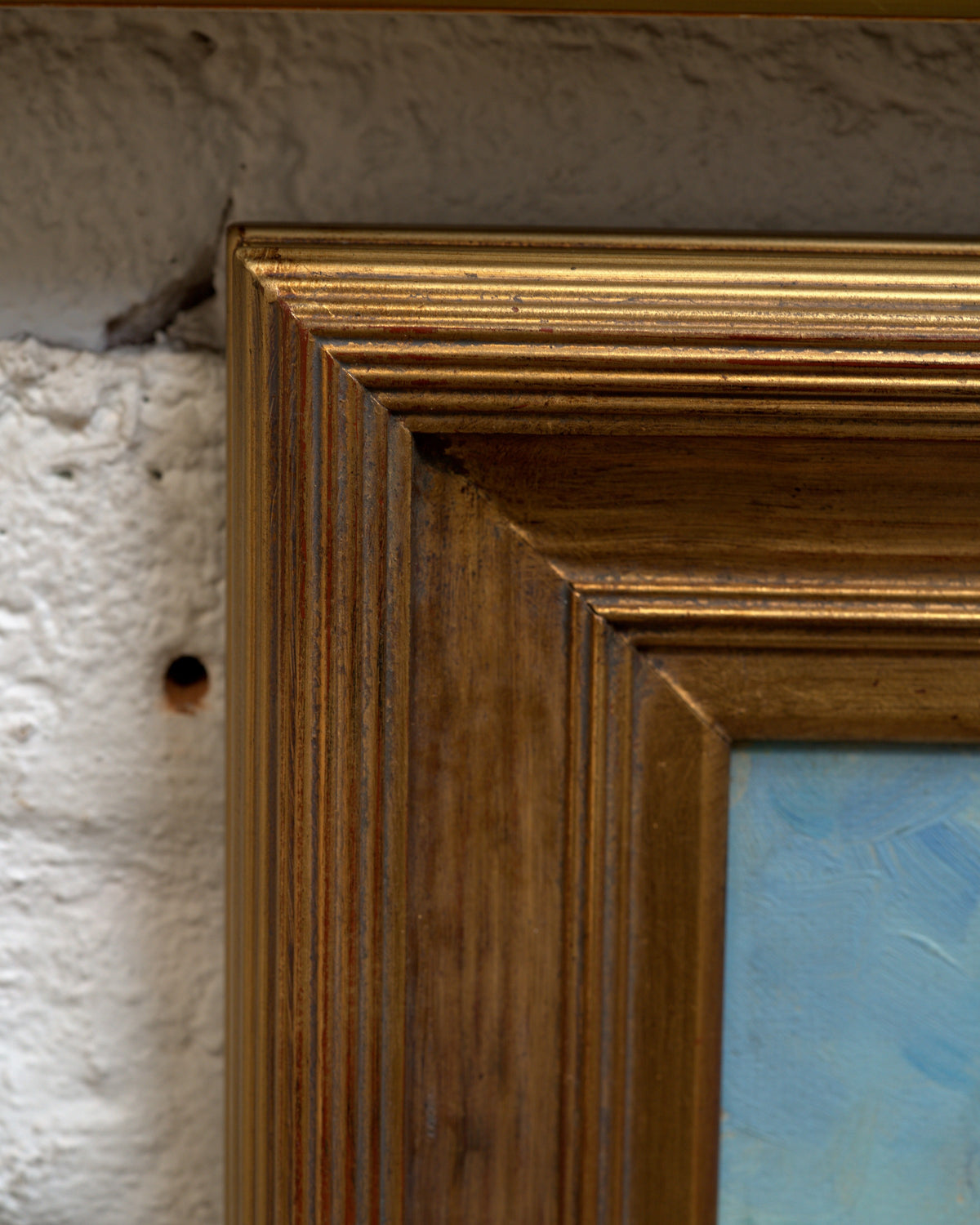 Corner of the frame on the Jack McCartney desert landscape with a green smoke tree, sage and rose hills in a stepped gilt frame.