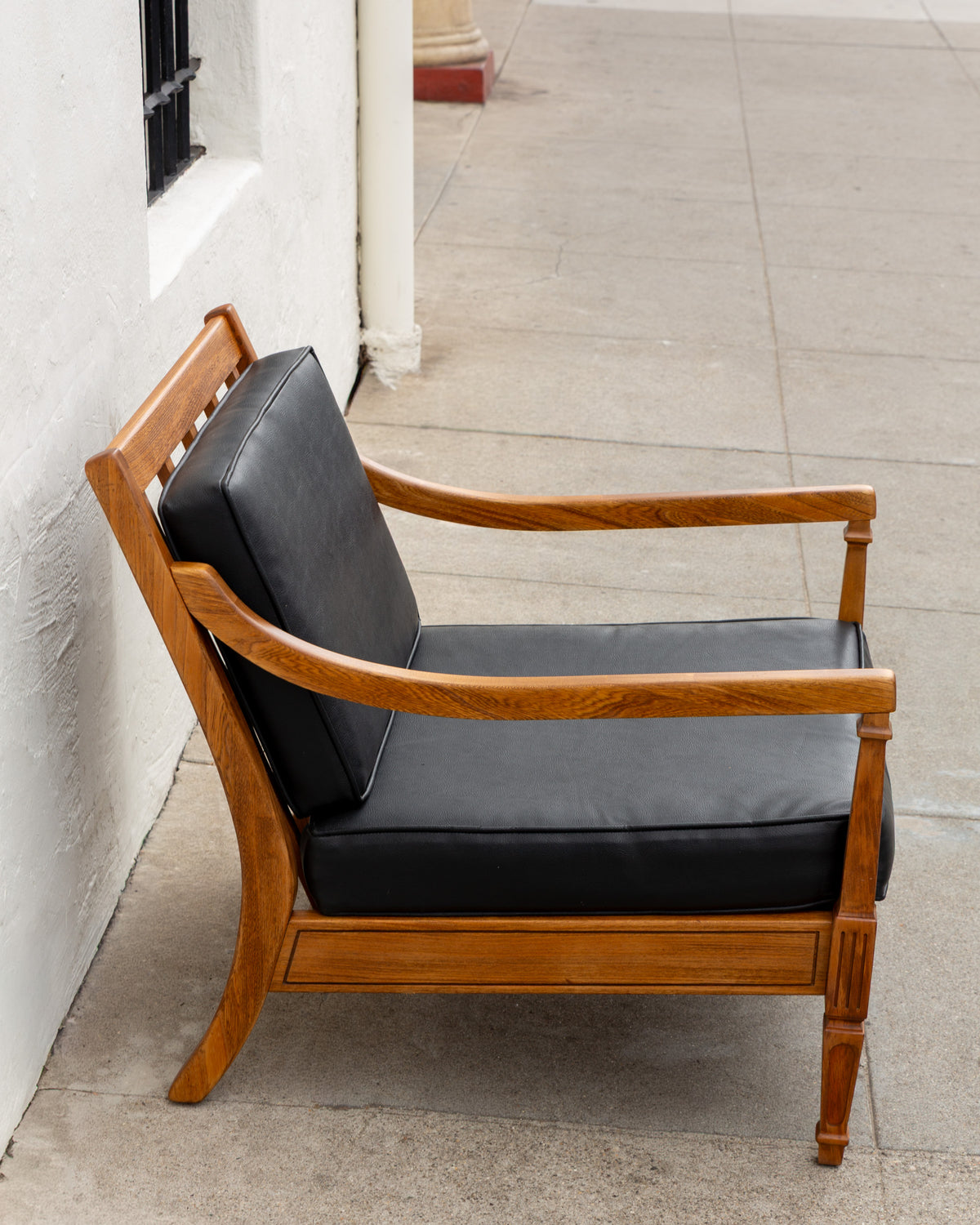 Side profile of the mid century arm chair showing the slatted back rail and the outward sweep of the back leg