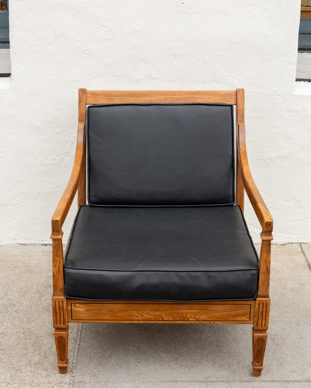 Straight-on front view of the mid century oak arm chair with black seat and back cushions