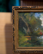 Angled view showing the frame depth of the miniature impressionist pond landscape in a carved dark gilt frame.