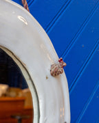 Detail of the knotted twisted cord passing through the top of the white ceramic mirror frame.