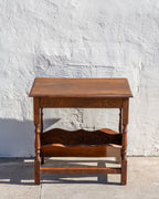 Front view of an oak side table with molded top, ring-turned legs and scalloped shelf below