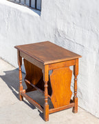 Three-quarter view from the end of an oak side table showing the shaped end panel and box stretcher
