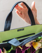 Interior of the black canvas tote, lined in green and white gingham with a zip pocket and the kate spade new york label.