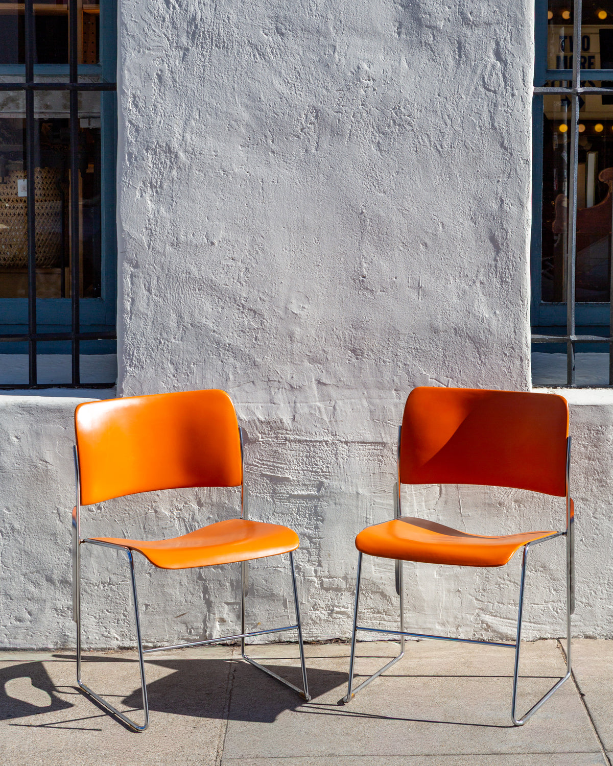 Front view of two orange 40/4 stacking chairs on chromed steel rod frames