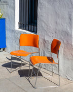 Angled view of a pair of orange David Rowland 40/4 chairs with chrome sled legs