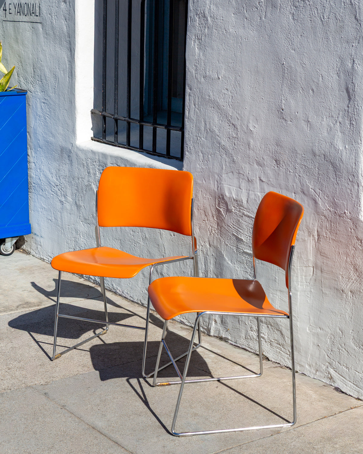 Angled view of a pair of orange David Rowland 40/4 chairs with chrome sled legs