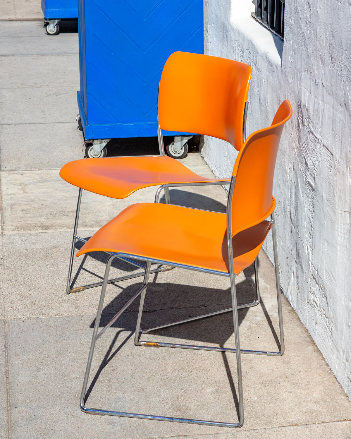 Two orange 40/4 chairs nested one on top of the other, showing how the chrome frames stack