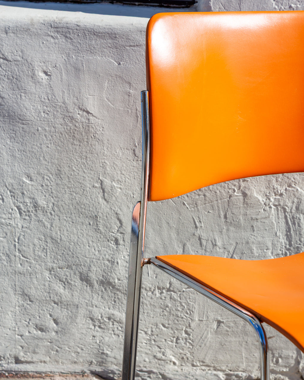 Close view of the curved orange back and chrome rod upright of a 40/4 stacking chair