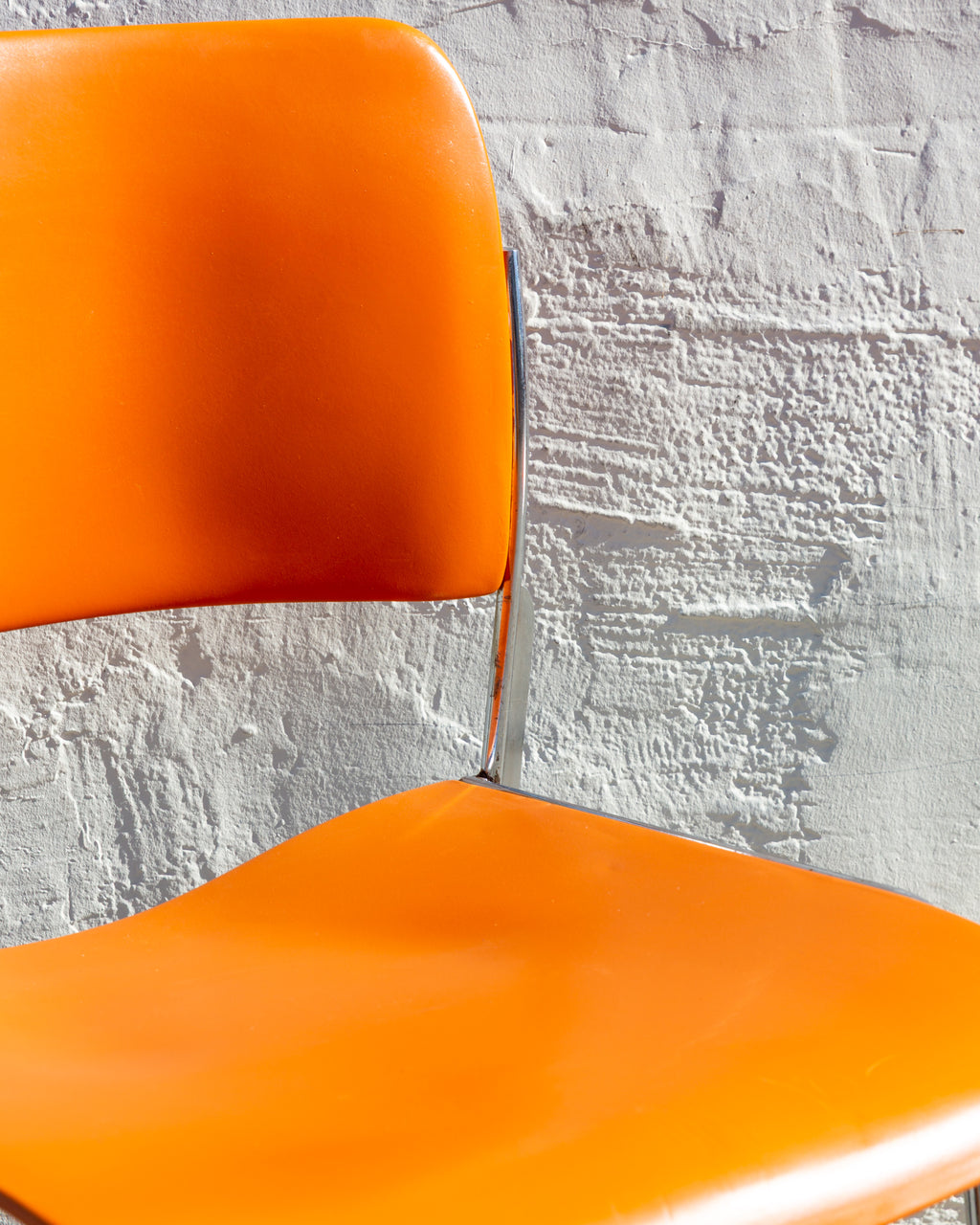 Detail of the orange seat and back meeting the chrome frame on a 40/4 chair