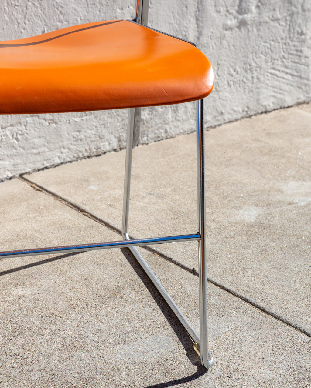 Detail of the orange seat edge, chrome legs and cross stretcher of a 40/4 chair