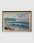 Straight-on view of a 1960s seascape of turquoise breaking waves, rocks and a misty headland in a whitewashed frame with linen liner, on a light gray background.