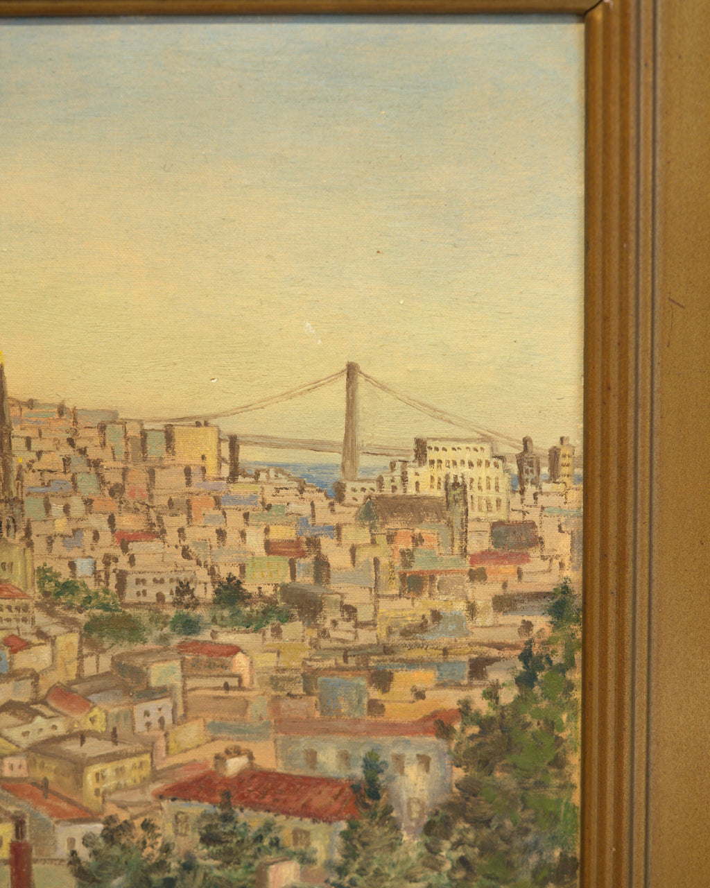 Close detail of the Bay Bridge above the rooftops in the vintage San Francisco cityscape painting, with the carved gilt frame edge.