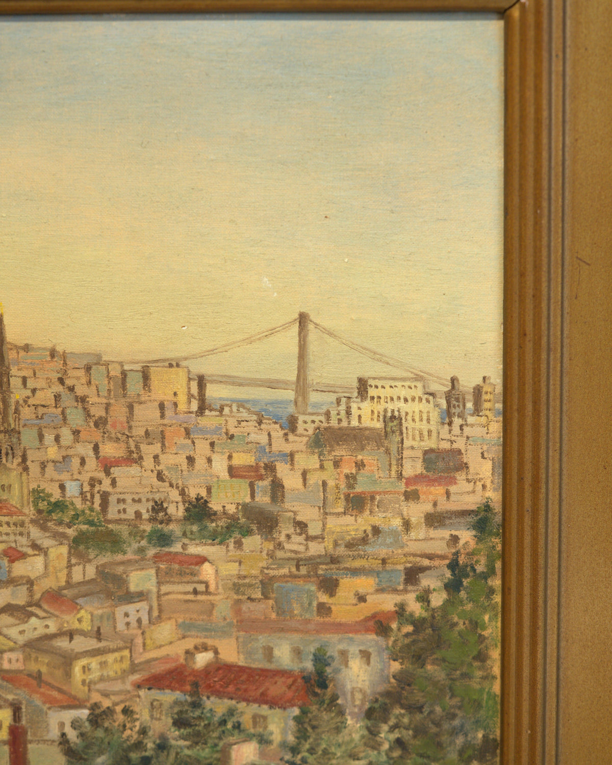 Close detail of the Bay Bridge above the rooftops in the vintage San Francisco cityscape painting, with the carved gilt frame edge.