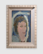 Straight-on view of a Sterling Strauser 1985 portrait An Actress, a pale face in a blue and white hood, in a whitewashed scored frame, on a light gray background.
