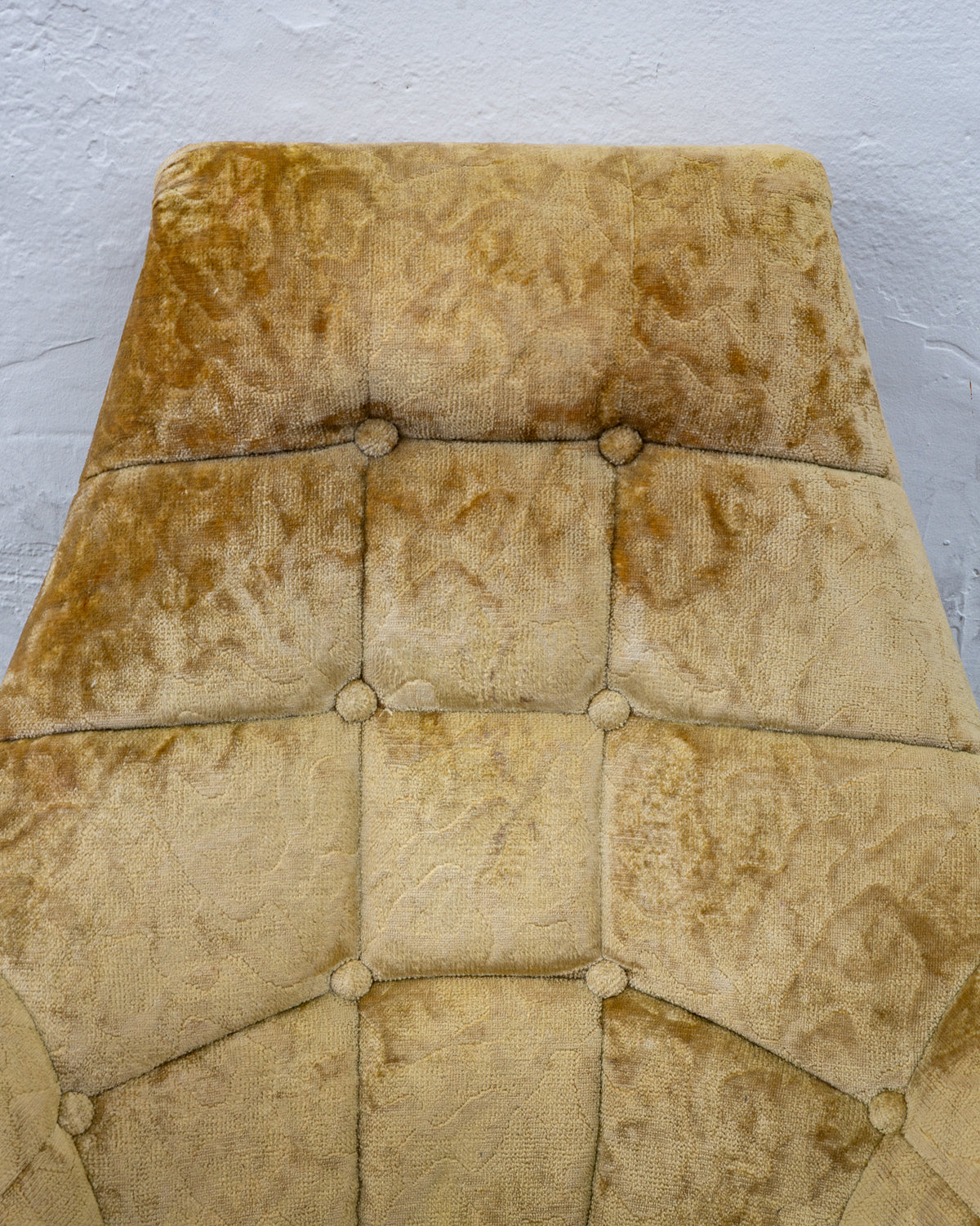 Overhead view down the button-tufted back of the chair, showing the grid of covered buttons and the damask pattern in the velvet