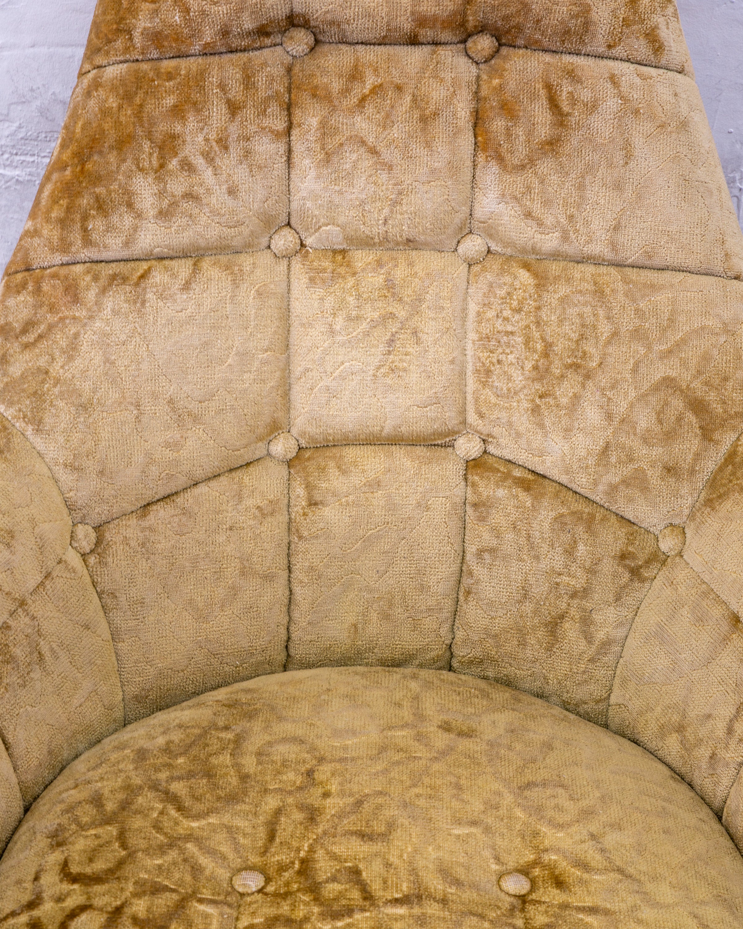 Overhead view of the tufted back meeting the rounded bucket seat in gold crushed velvet