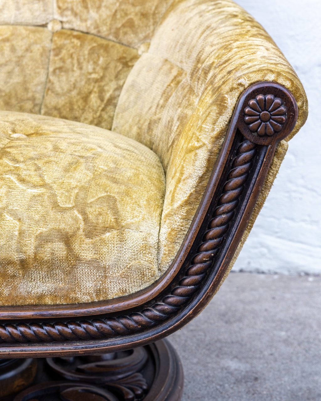 Detail of a carved rosette arm terminal with rope twist molding running along the arm, beside the velvet seat