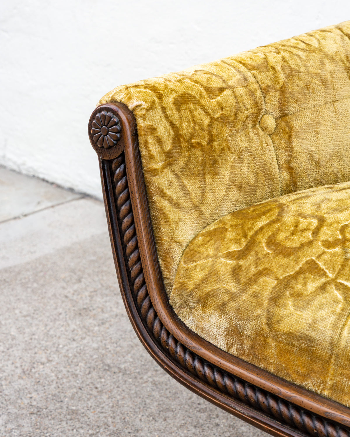Detail of the carved wooden rosette at the front corner of the arm, with rope twist molding and gold velvet upholstery